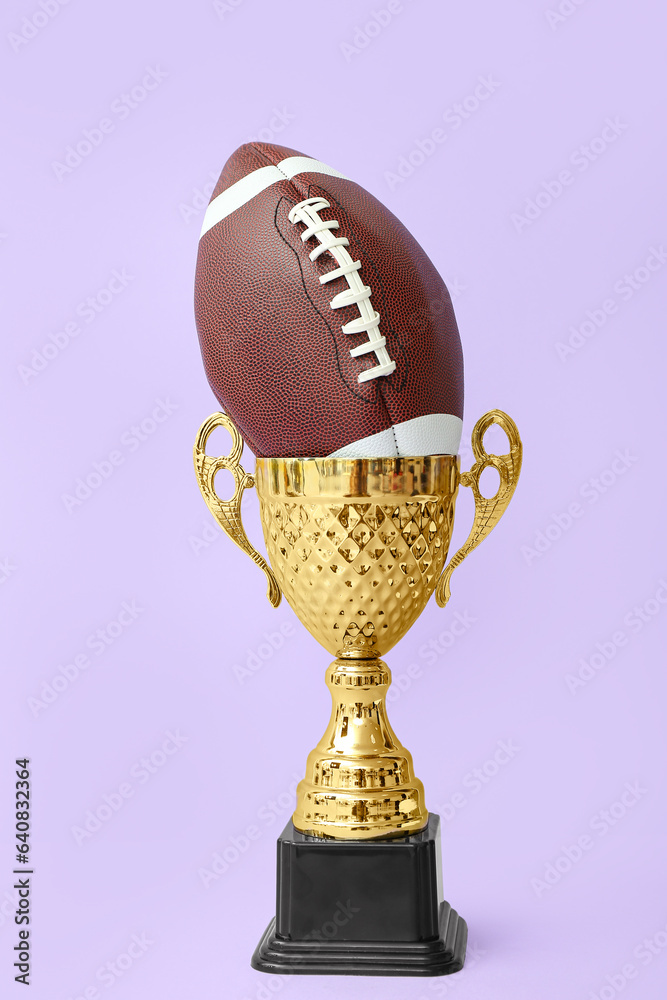 Gold cup with rugby ball on lilac background