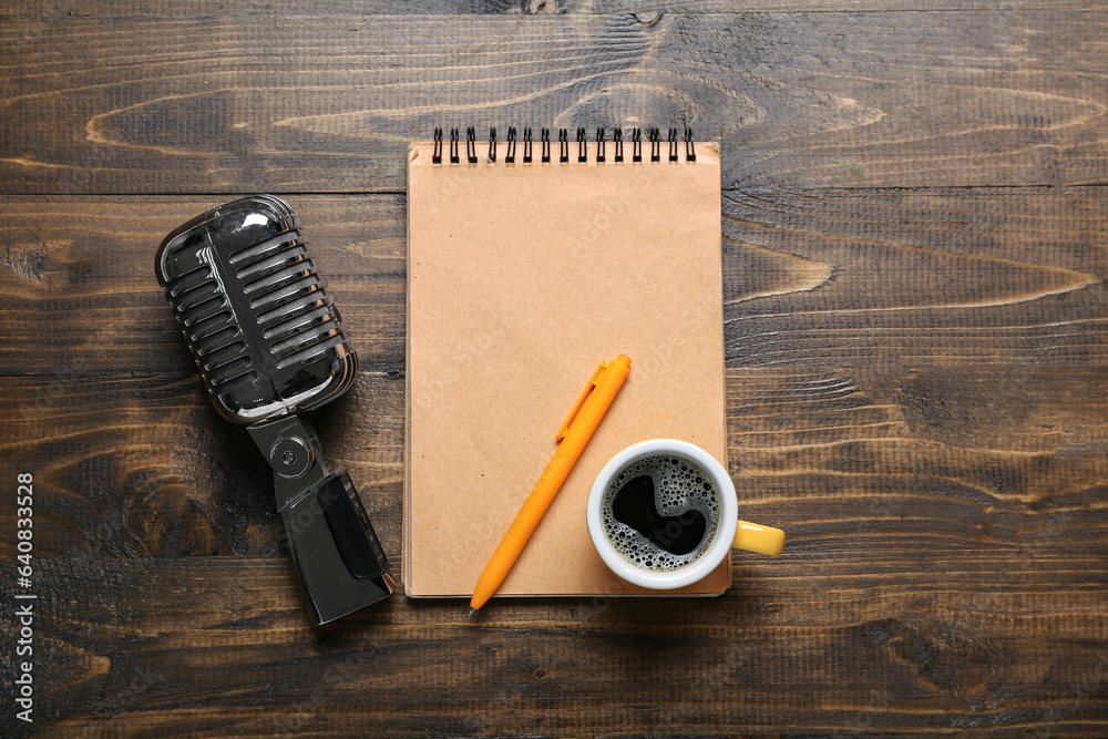 Notebook with cup of coffee and microphone on dark wooden background