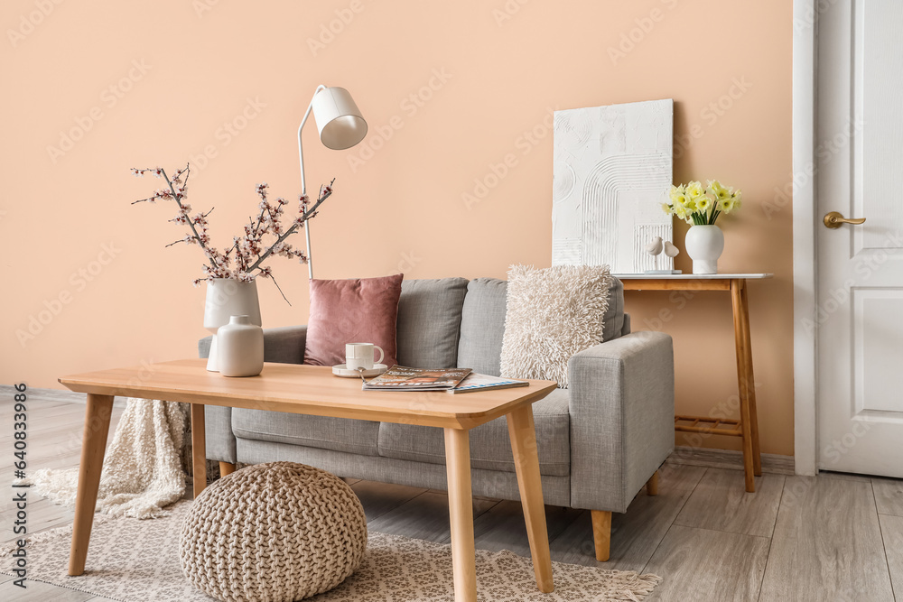 Interior of living room with grey sofa, tables and lamp