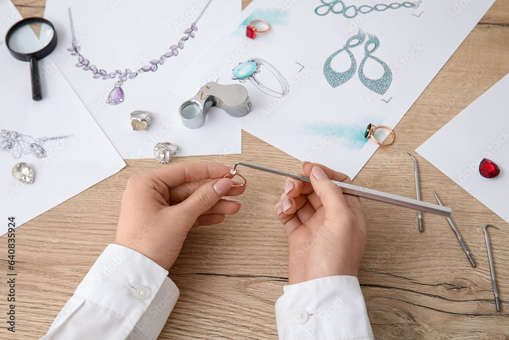 Female jeweler making ring on wooden table, closeup