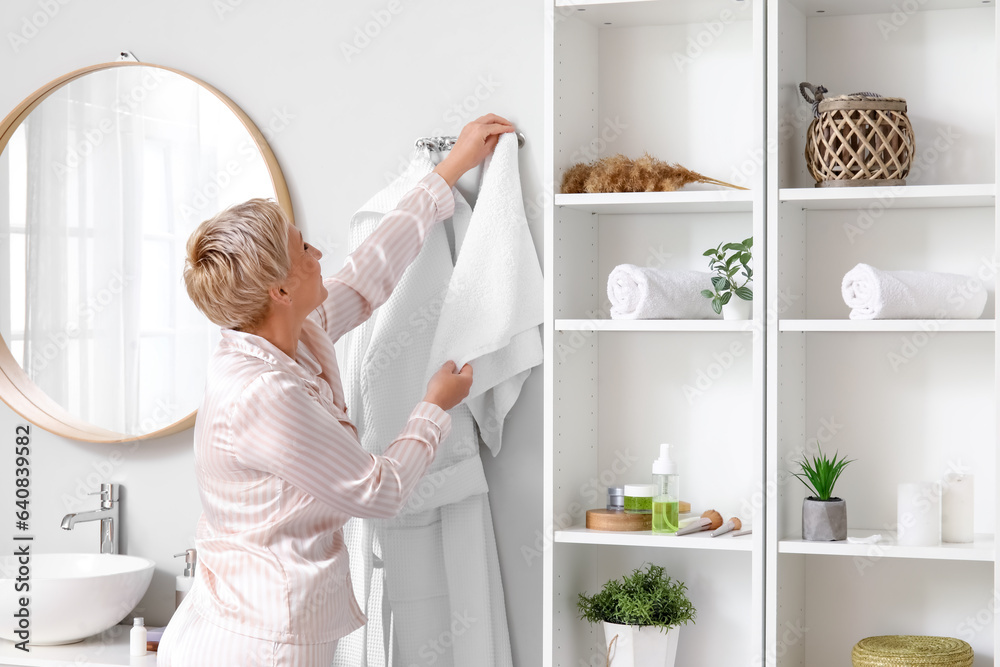 Mature woman taking towel in bathroom