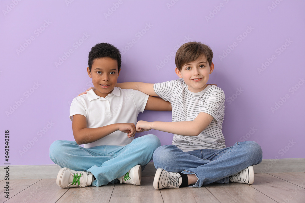 Cute little boys hugging near lilac wall