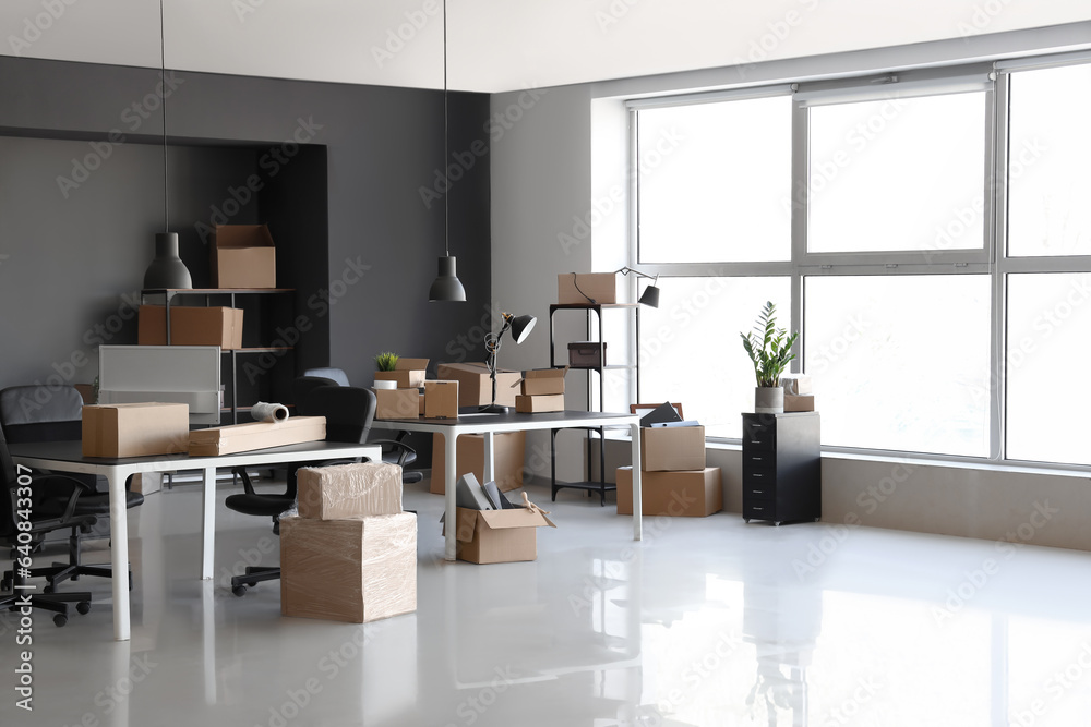 Interior of modern office with cardboard boxes on moving day