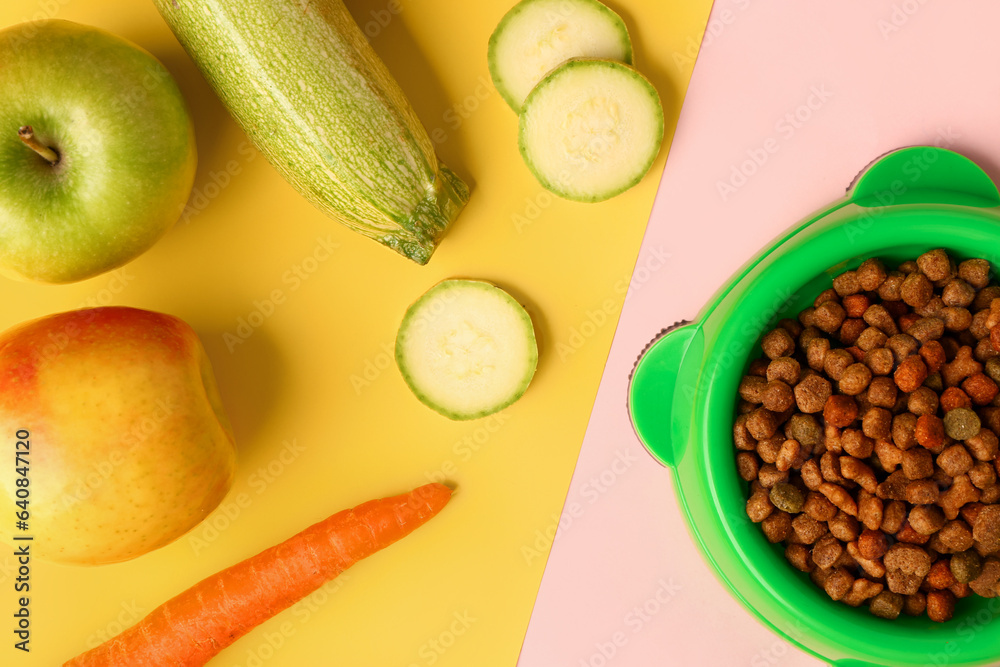 Bowl with dry pet food and natural products on color background, closeup