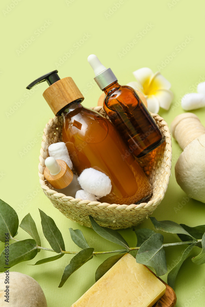 Basket with cosmetic products and eucalyptus branch on color background