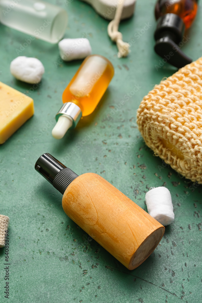 Bottles of cosmetic products and bath supplies on green background