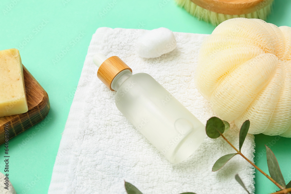 Bottle of essential oil and bath supplies on color background, closeup