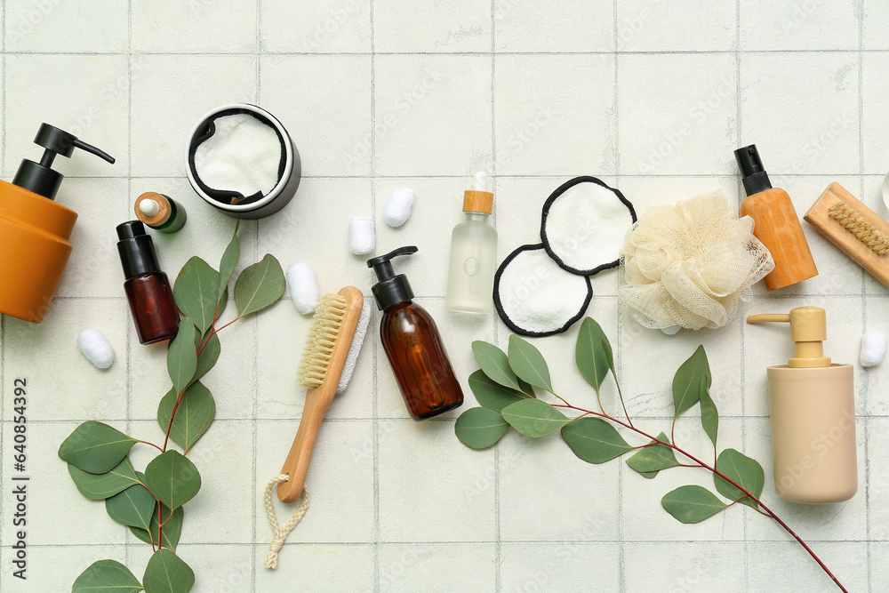 Composition with different bath supplies, cosmetic products and eucalyptus branches on light tile ba