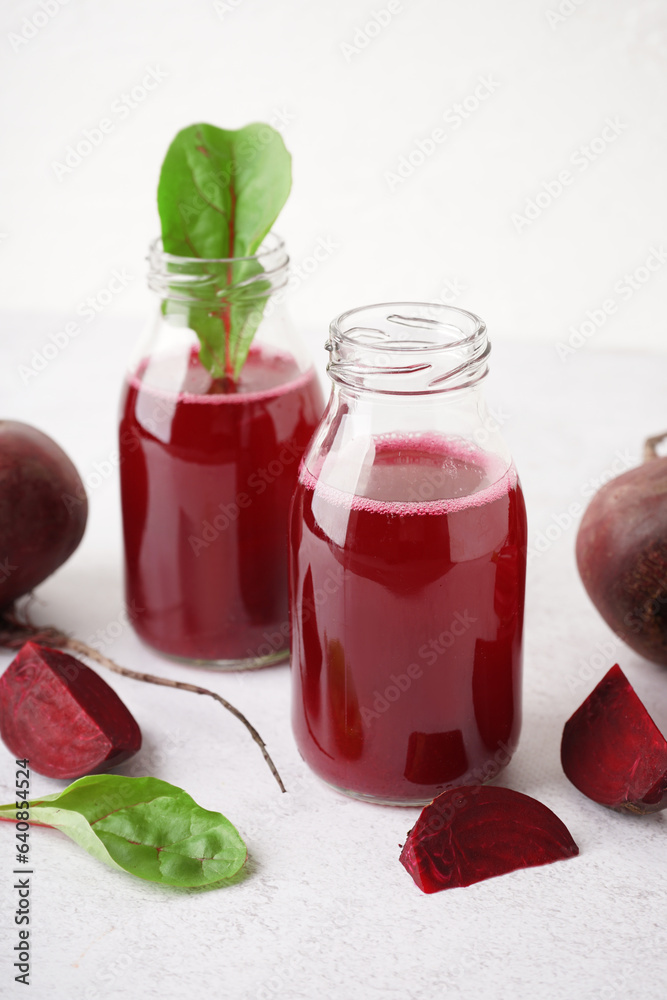 Bottles of fresh beetroot juice on light background