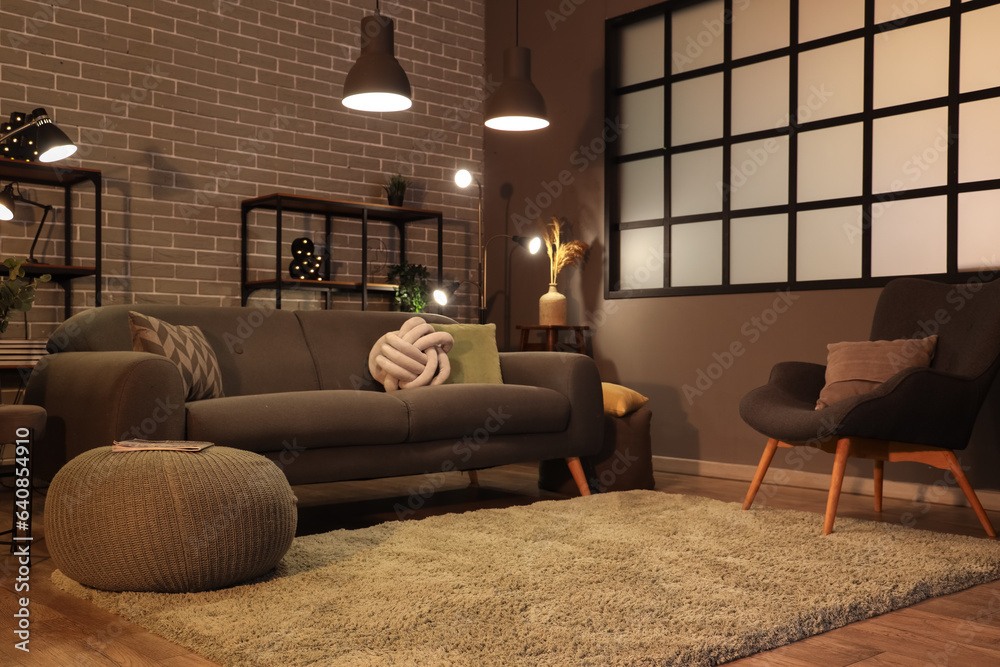 Interior of dark living room with cozy grey sofa and glowing lamps