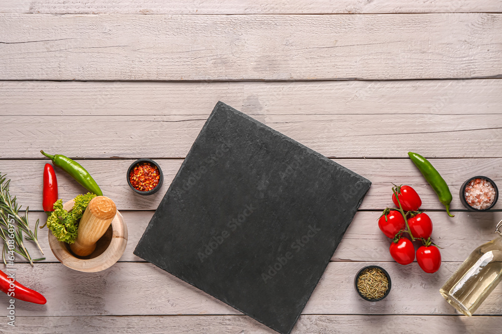 Composition with slate board, spices and vegetables on light wooden background