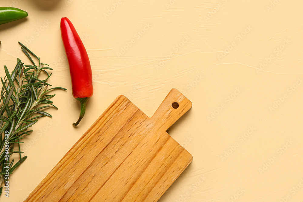 Wooden cutting board, chili peppers and rosemary on color background