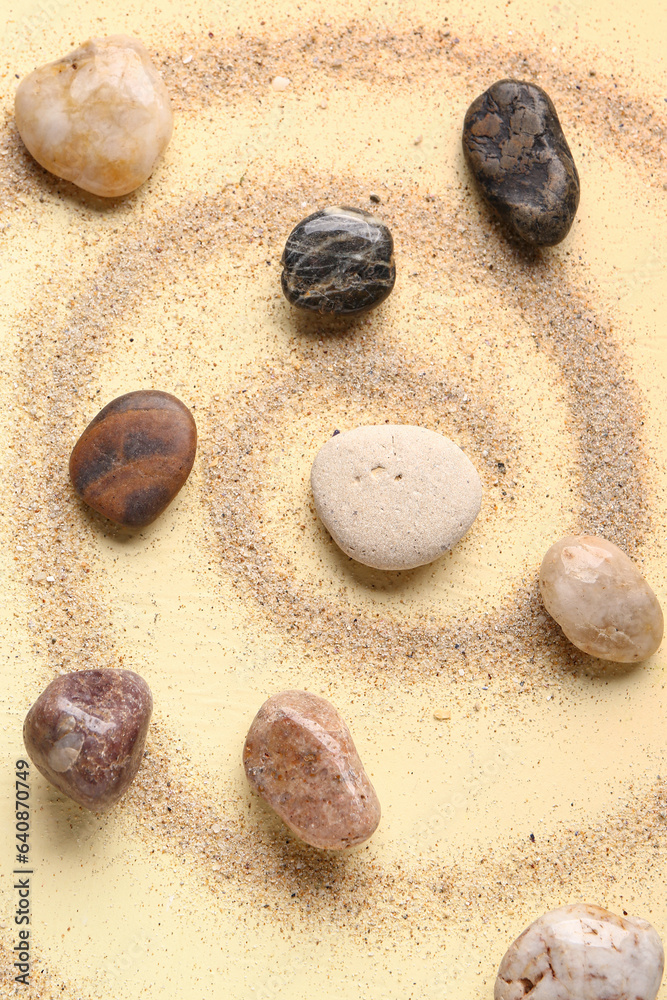 Many pebble stones and sand on yellow background