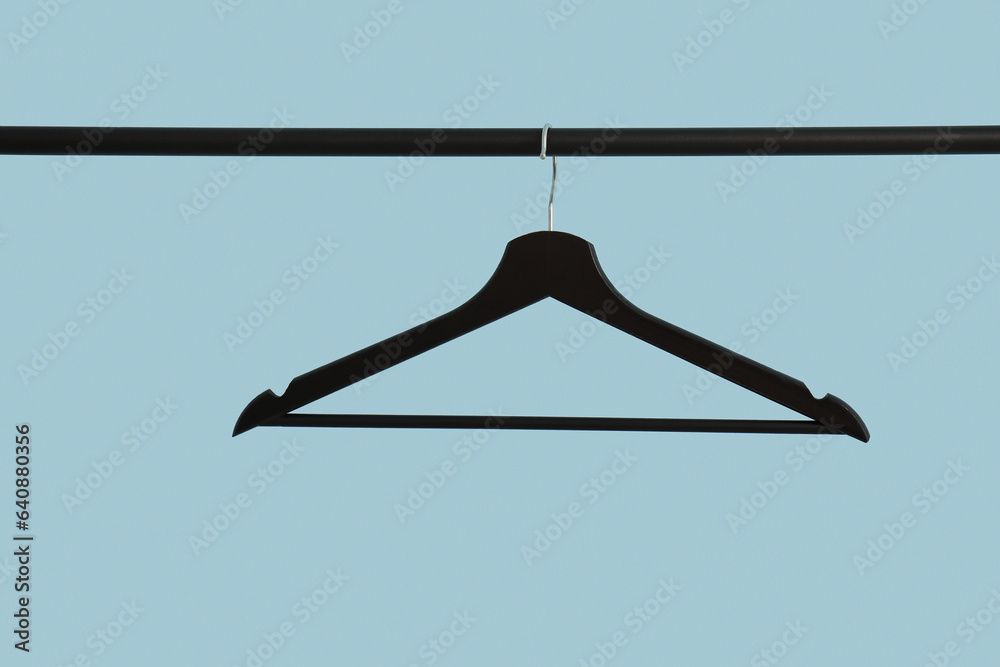 Rack with black clothes hanger on blue background