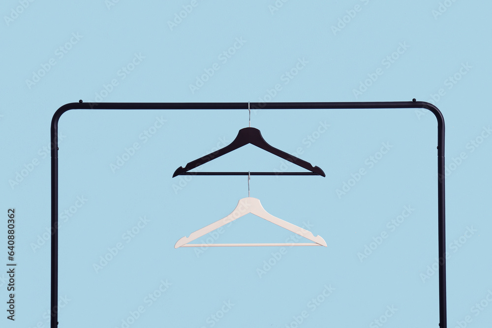 Rack with wooden clothes hangers on blue background