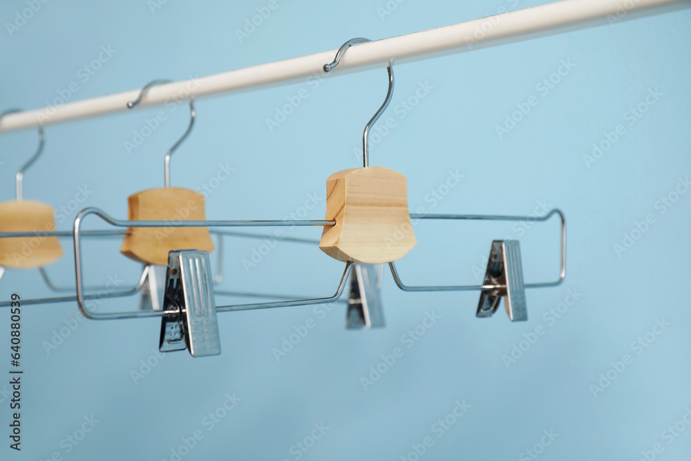 Rack with metal clothes hangers on blue background