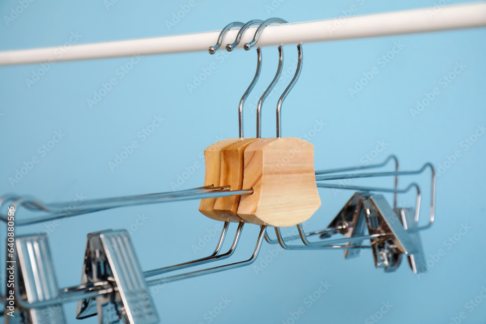 Rack with metal clothes hangers on blue background