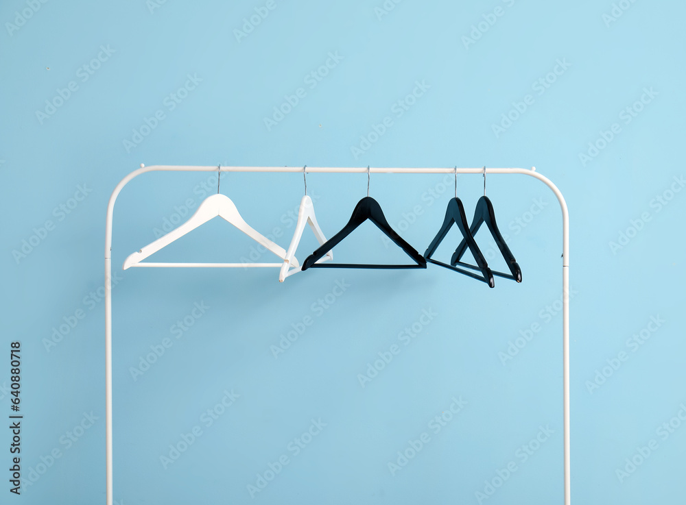 Rack with wooden clothes hangers on blue background