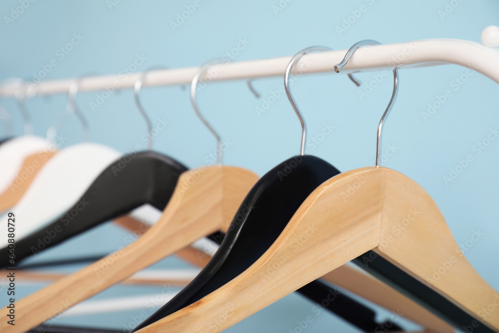 Rack with wooden clothes hangers on blue background