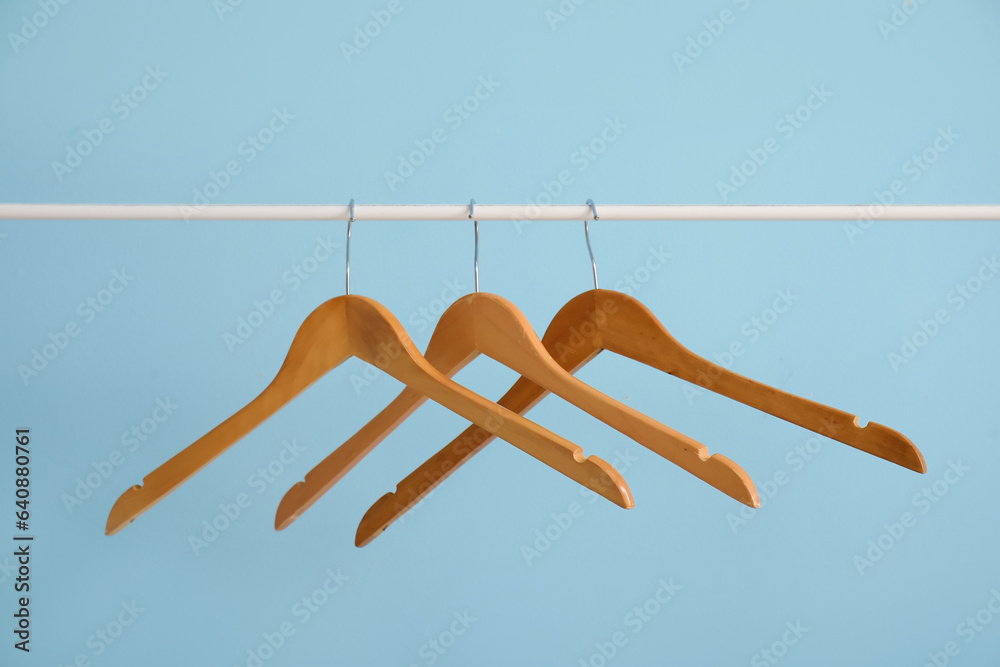 Rack with wooden clothes hangers on blue background