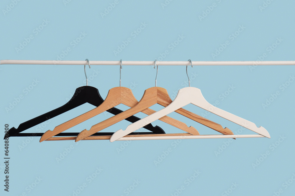 Rack with wooden clothes hangers on blue background