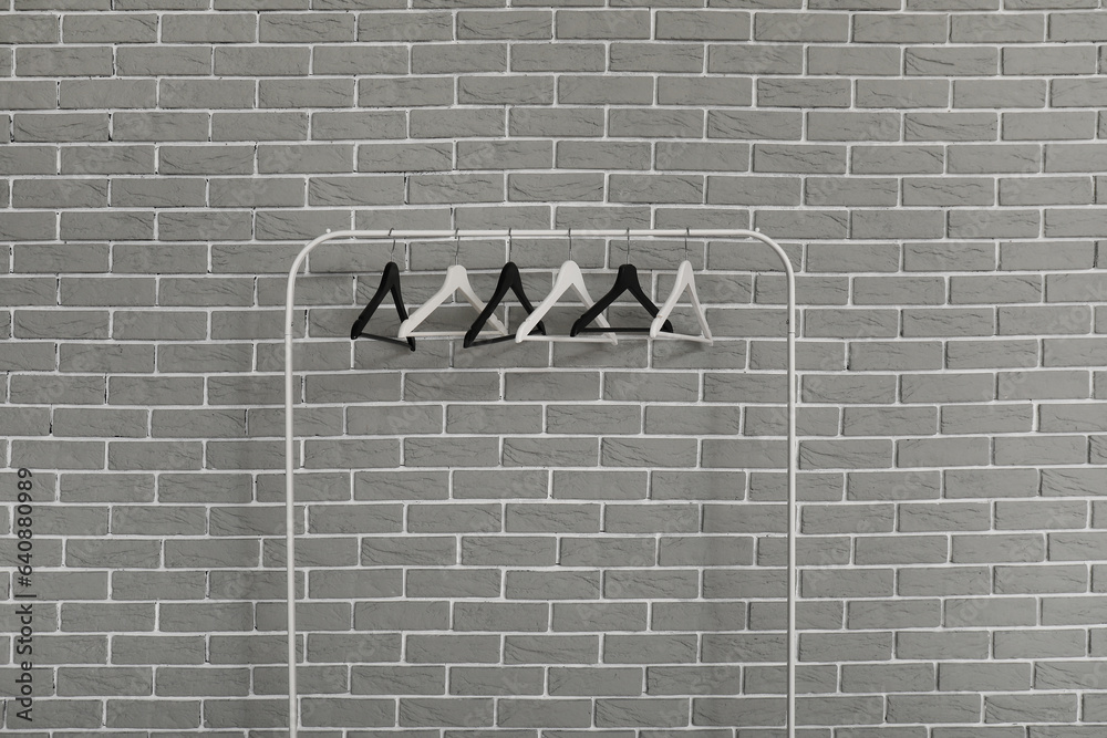 Rack with wooden clothes hangers on grey brick wall background