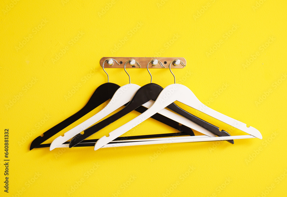 Rack with wooden clothes hangers on yellow background