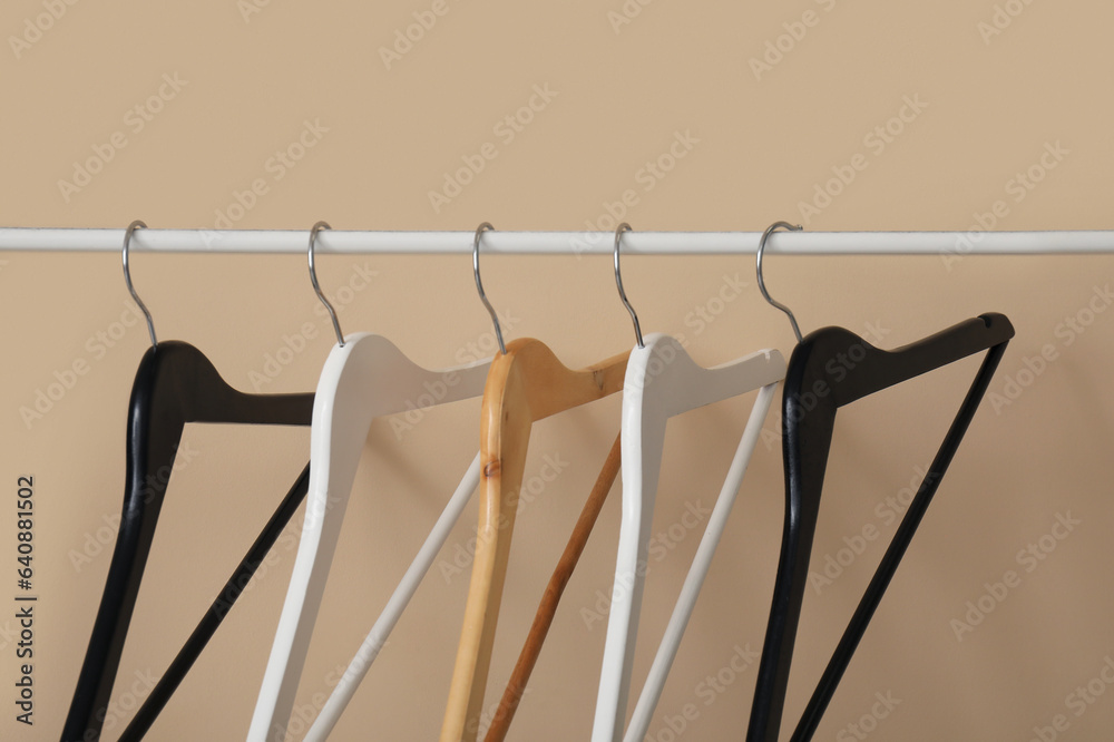 Rack with wooden clothes hangers on beige background