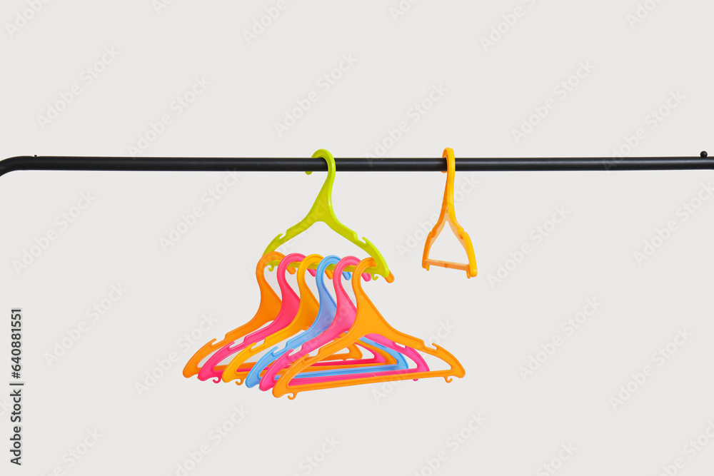 Rack with plastic clothes hangers on grey background