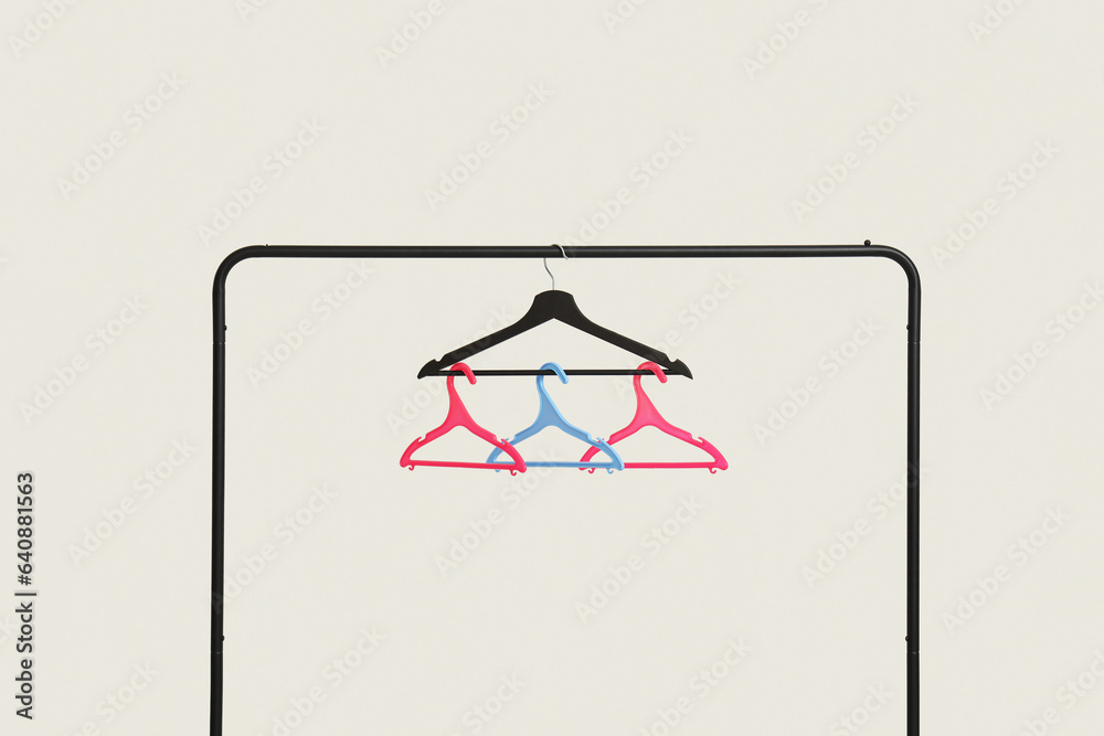 Rack with plastic clothes hangers on grey background