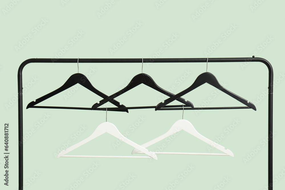 Rack with wooden clothes hangers on green background