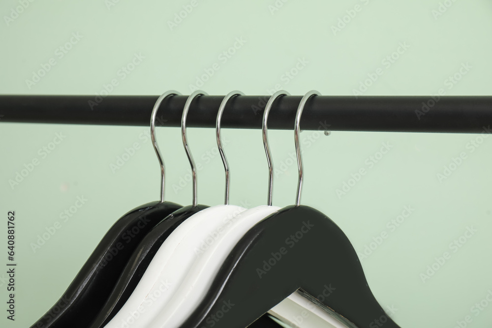 Rack with wooden clothes hangers on green background