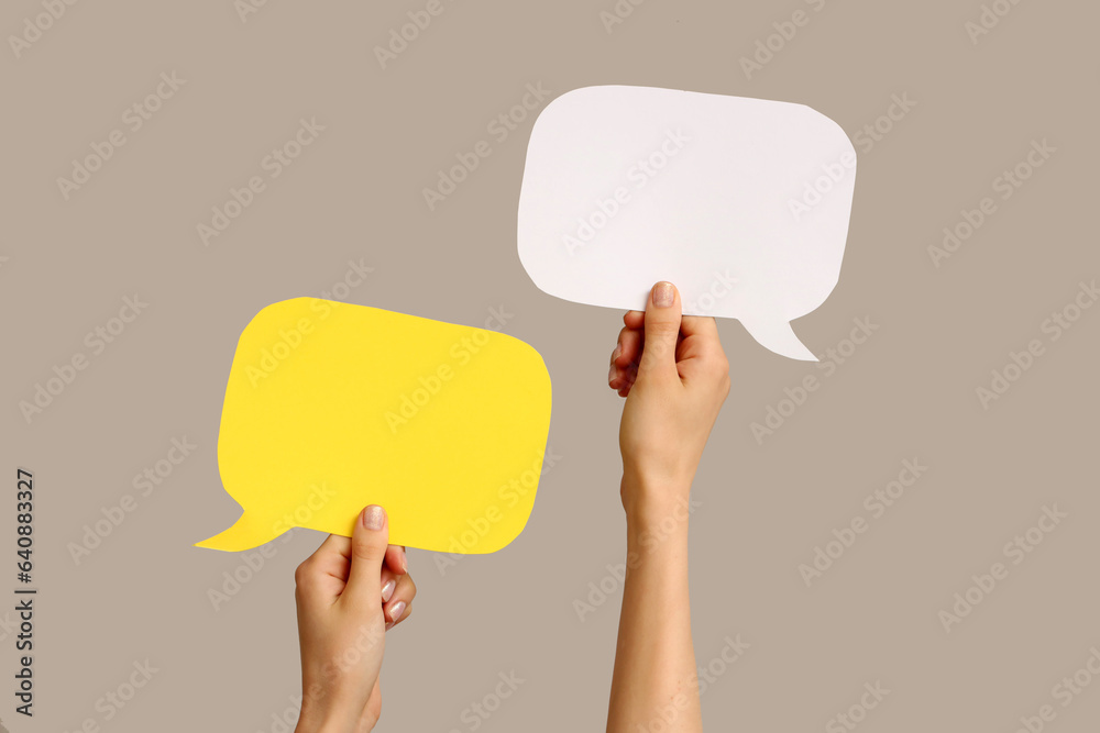 Female hands with speech bubbles on grey background