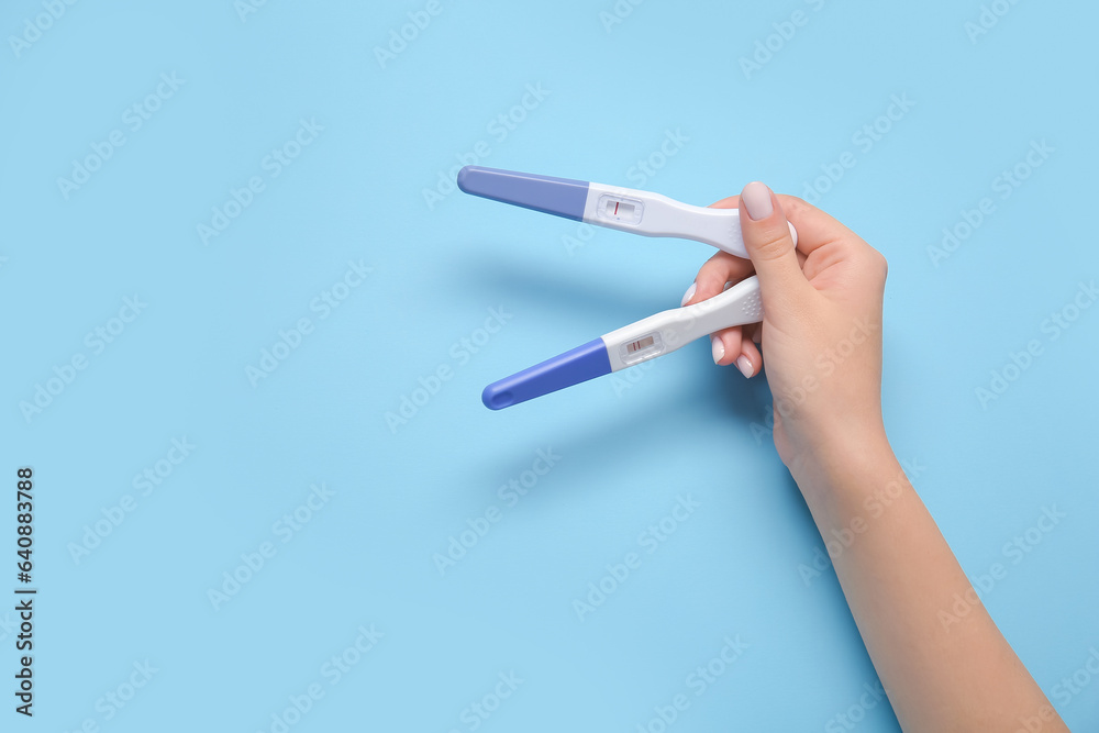 Female hand with pregnancy tests on color background