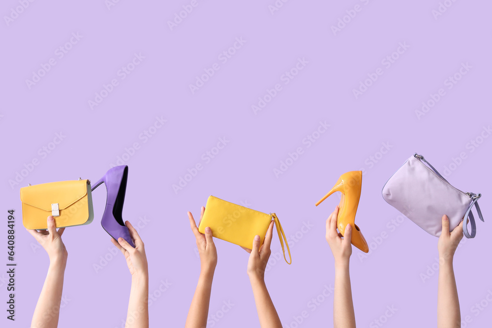 Female hands holding different stylish bags and high heels on lilac background