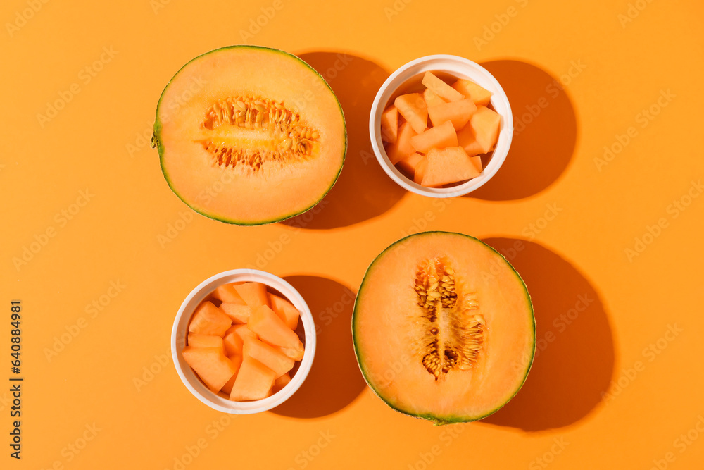 Halves of sweet melon and bowls with pieces on orange background