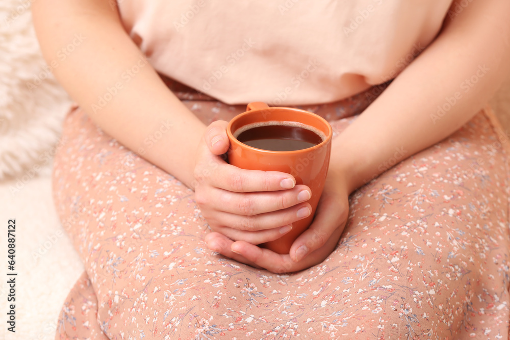 Woman holding cup of tasty coffee at home, closeup