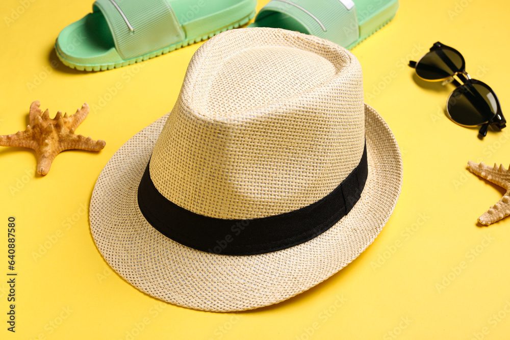 Stylish hat, sunglasses and flip-flops on color background