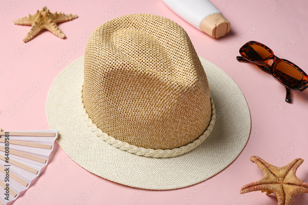 Stylish straw hat, sunglasses, sunscreen cream and starfishes on color background