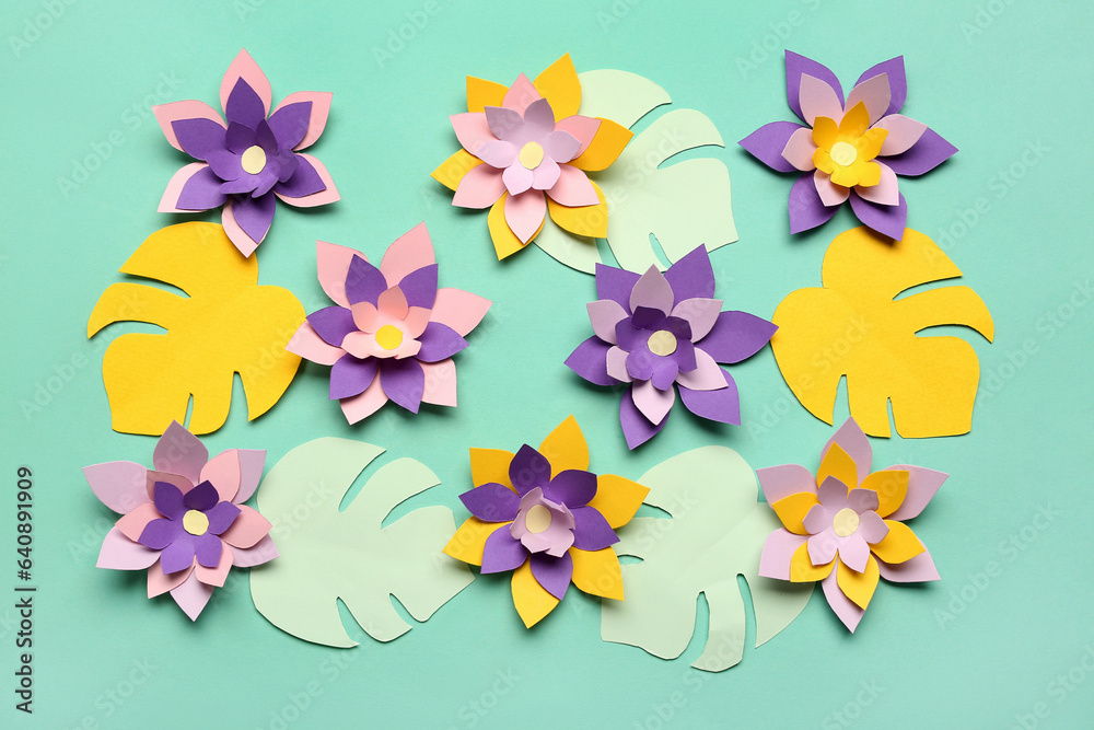 Colorful origami flowers with leaves on green background