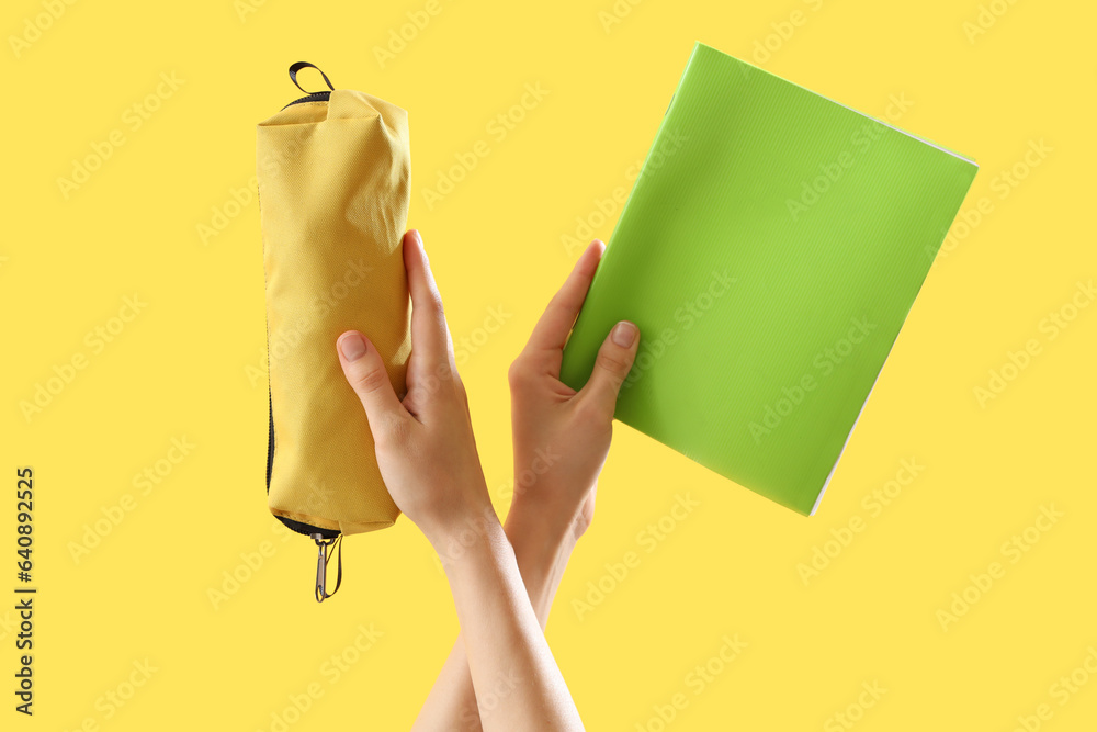 Female hands with different stationery on yellow background