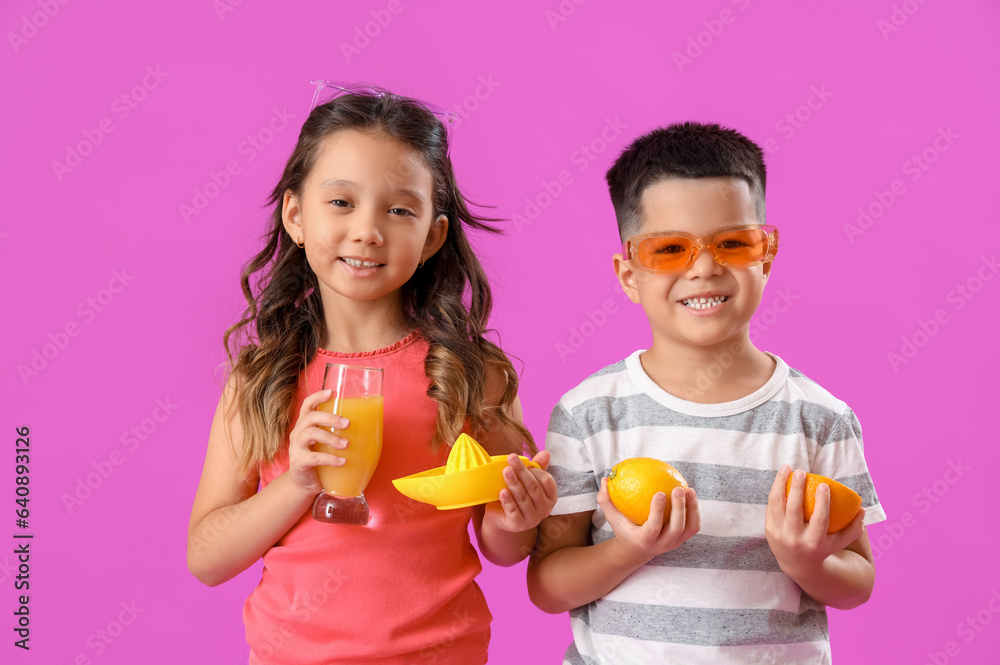 Little Asian children with fresh citrus juice, fruits and squeezer on purple background