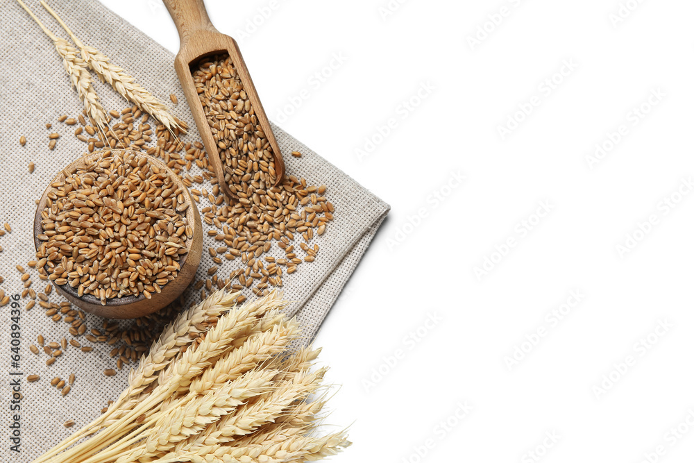 Wooden bowl with grains, wheat ears and scoop on white background