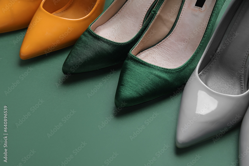 Different stylish high heels on green background