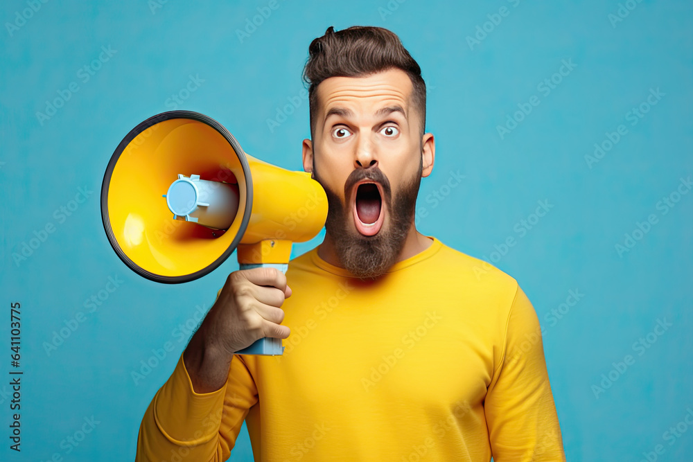 Surprised face of young bearded man wears blue shirt hold scream in megaphone announces discounts sa