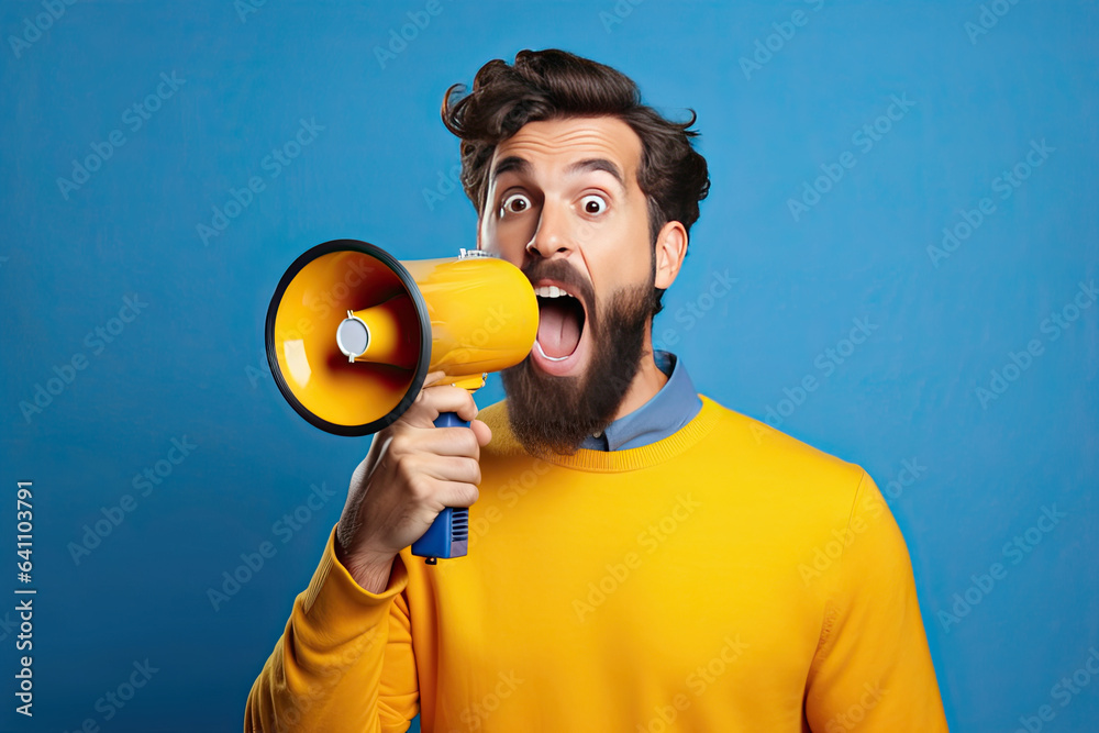 Surprised face of young bearded man wears blue shirt hold scream in megaphone announces discounts sa