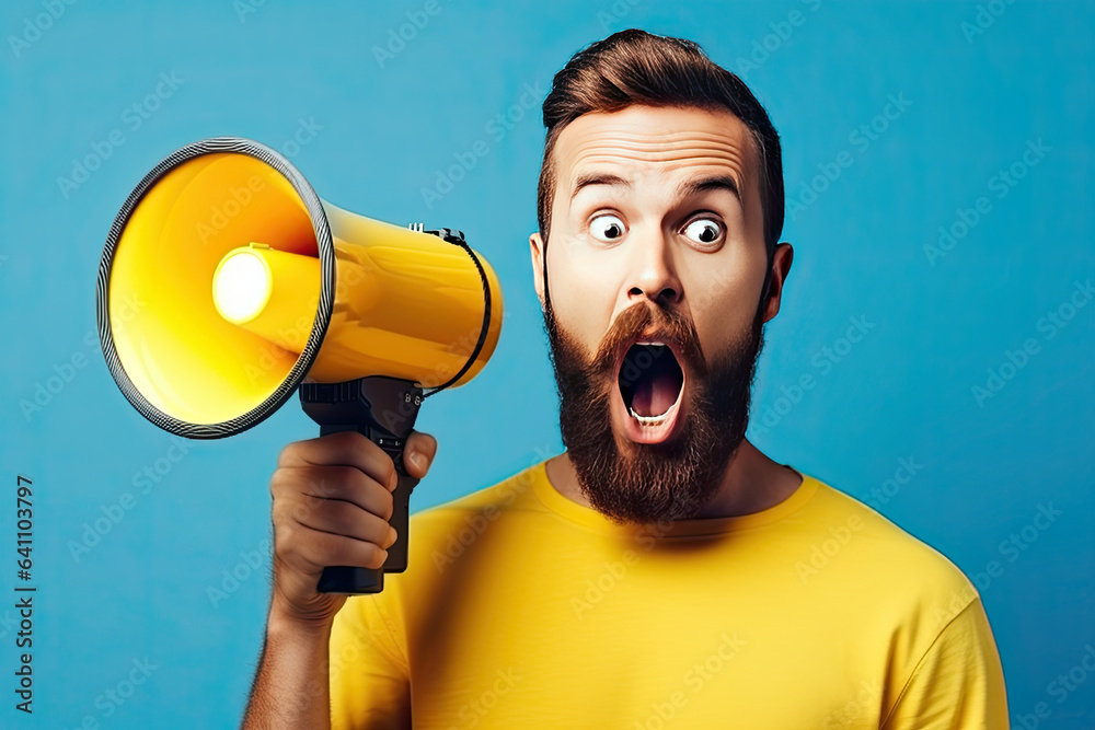 Surprised face of young bearded man wears blue shirt hold scream in megaphone announces discounts sa