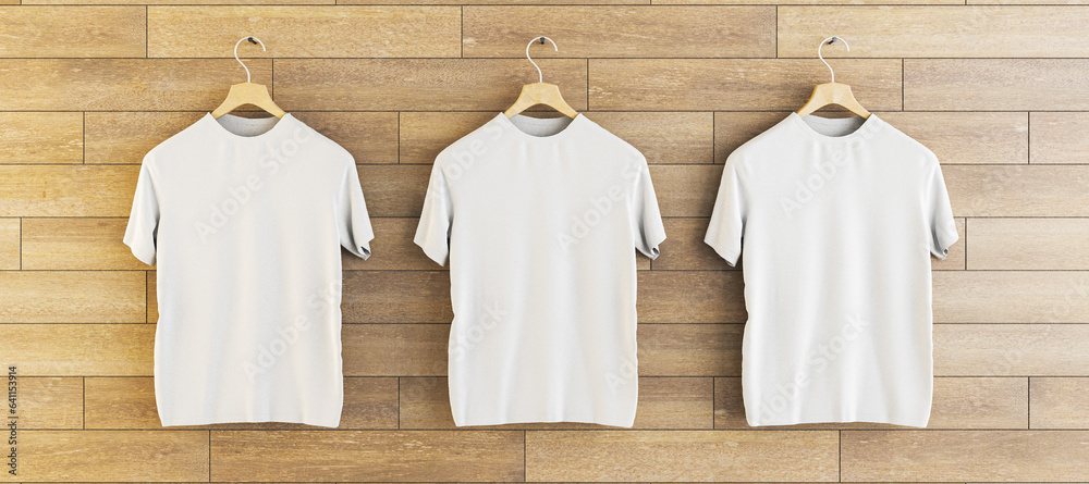 Three empty white t-shirts hanging on wooden wall background. Ad, textile and fashion concept. 3D Re