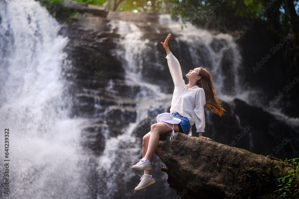 asian woman traveller relaxing in deep tropical jungle waterfall 