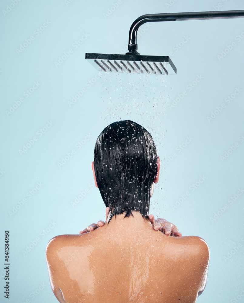 Woman, shower and back in water drops for washing, grooming or hygiene against a blue studio backgro